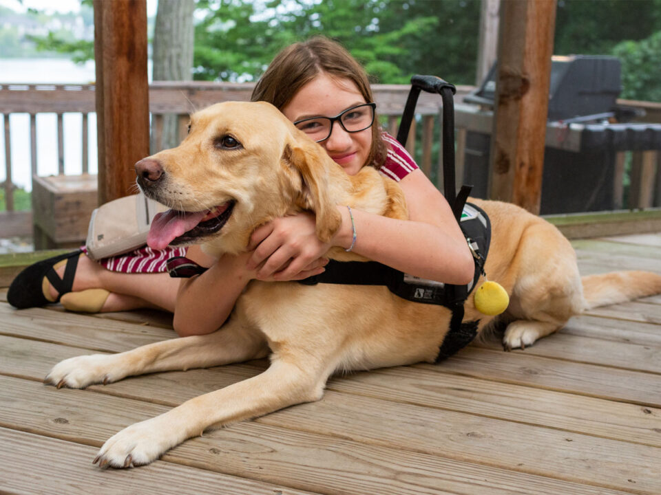 a young girl on a deck holding her service dog